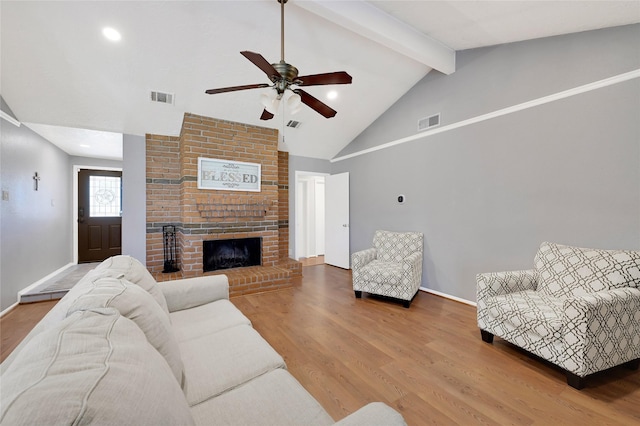 living room with visible vents, beamed ceiling, a fireplace, and wood finished floors