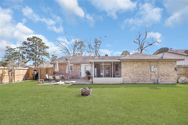 rear view of house with a fire pit, a lawn, a fenced backyard, a patio area, and brick siding