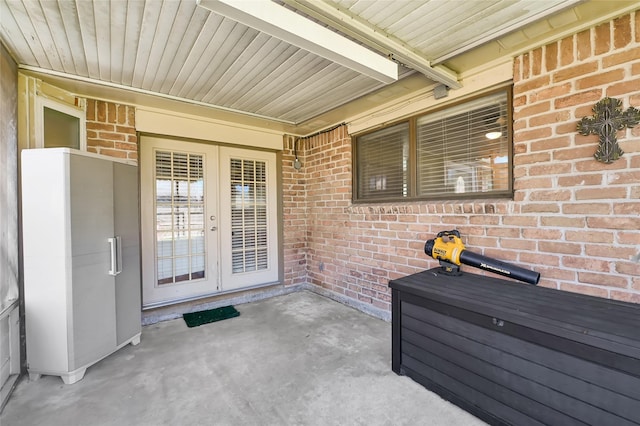 view of exterior entry with a patio area, french doors, and brick siding