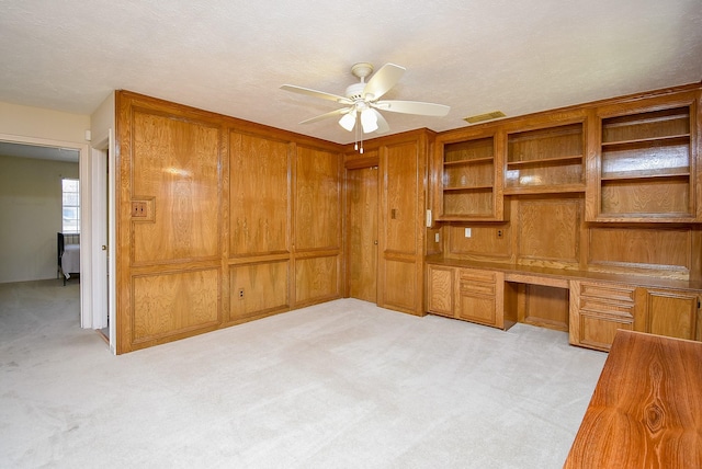 office area with a ceiling fan, visible vents, built in desk, a textured ceiling, and light carpet