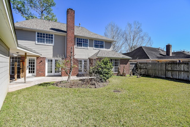 rear view of house with fence, a yard, brick siding, a chimney, and a patio area