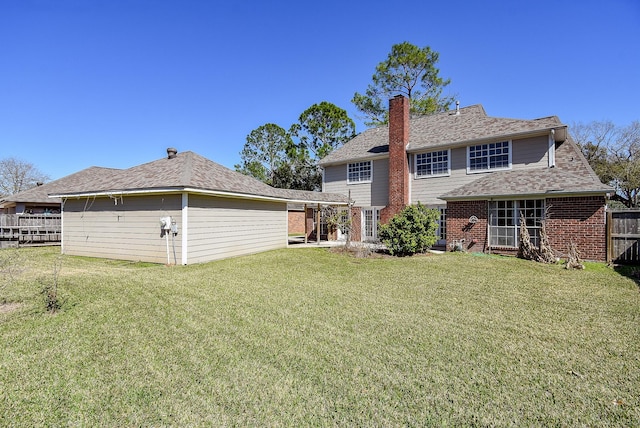 rear view of property with fence, a lawn, brick siding, and a chimney