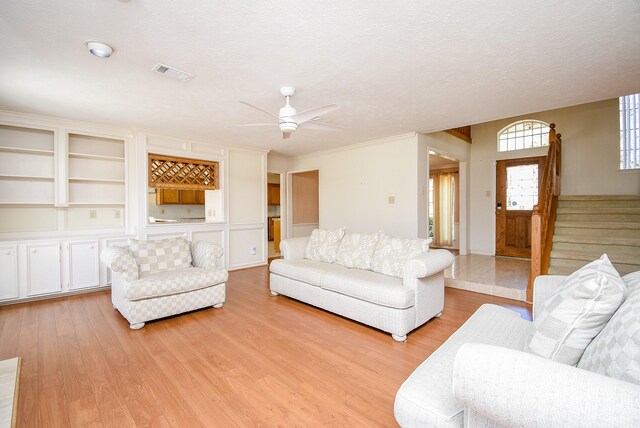 living area with visible vents, a textured ceiling, light wood-style flooring, and stairway