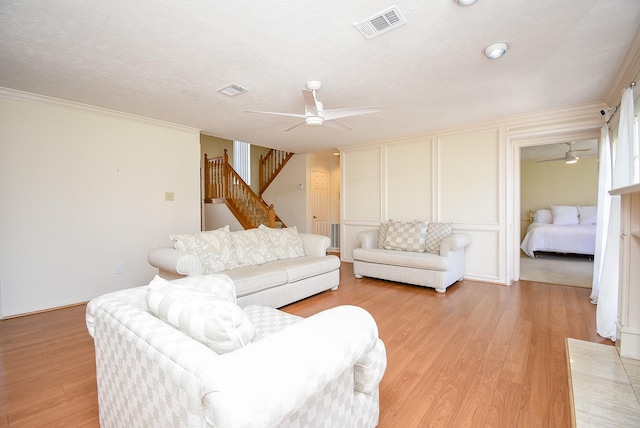 living area featuring visible vents, stairway, a decorative wall, and light wood-style floors