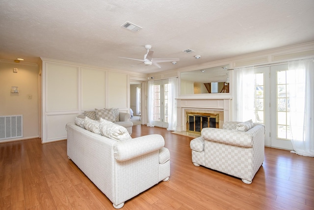 living area with visible vents, plenty of natural light, a decorative wall, and light wood-style floors