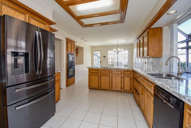 kitchen featuring a sink, black appliances, a peninsula, and brown cabinetry