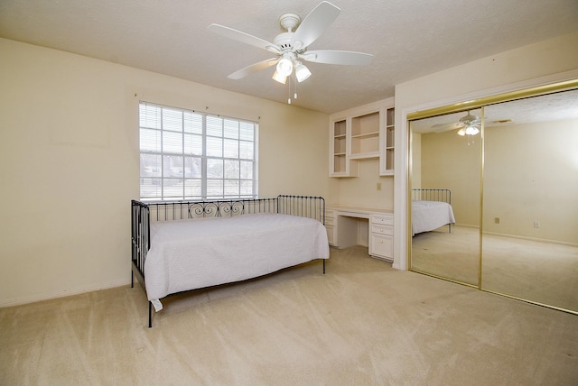 bedroom with built in desk, light colored carpet, and a textured ceiling