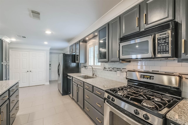 kitchen with visible vents, a sink, ornamental molding, stainless steel appliances, and backsplash