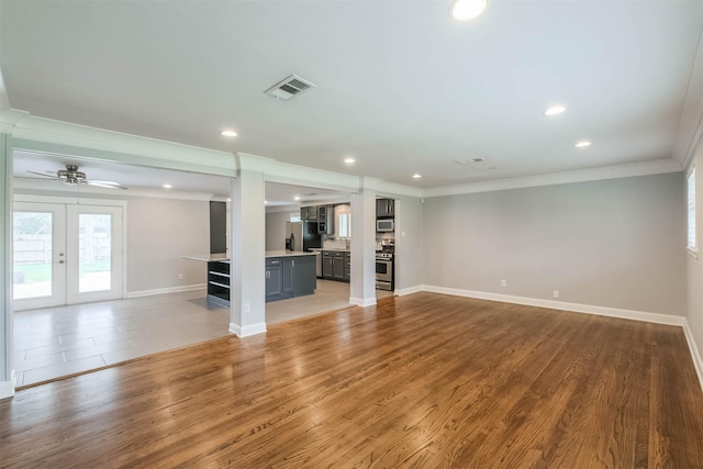 unfurnished living room with crown molding, french doors, visible vents, and light wood-type flooring