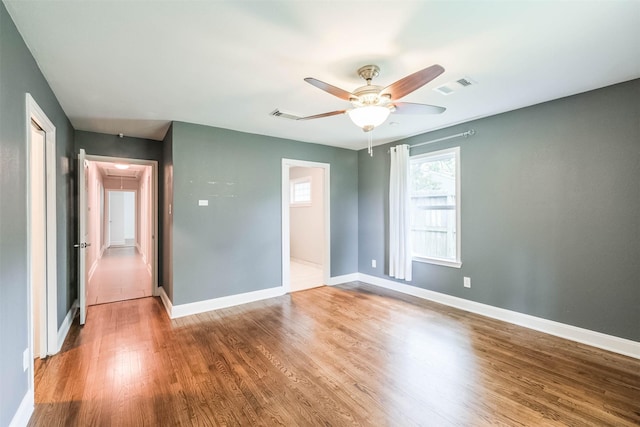 unfurnished bedroom featuring visible vents, baseboards, attic access, and wood finished floors