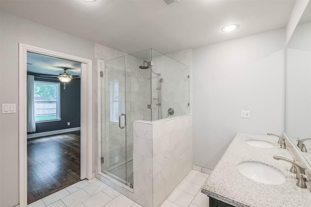 bathroom with double vanity, a shower stall, and a sink