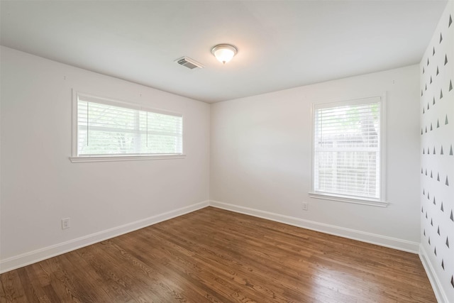 unfurnished room with visible vents, baseboards, and wood finished floors