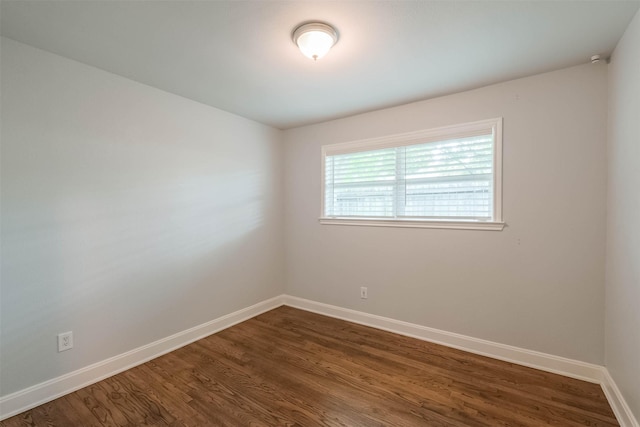 unfurnished room featuring baseboards and dark wood-type flooring