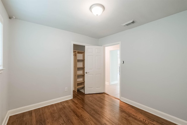 unfurnished bedroom with a closet, visible vents, baseboards, and wood finished floors