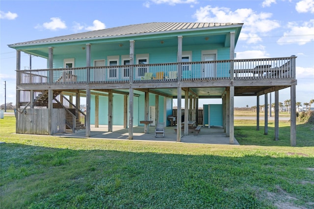 rear view of house with a yard, stairs, metal roof, and a patio