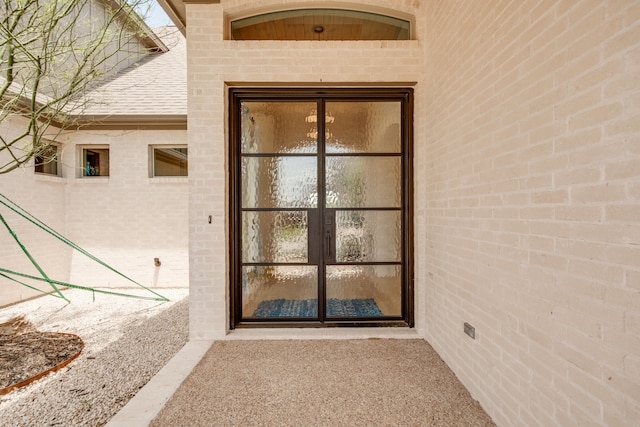 property entrance featuring brick siding and roof with shingles