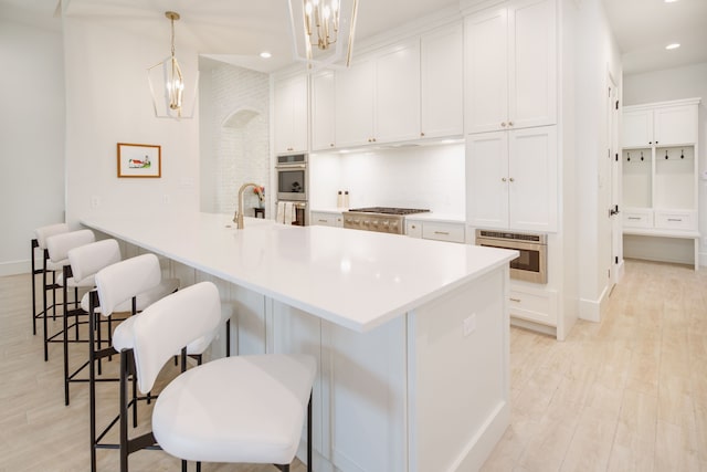 kitchen featuring gas cooktop, white cabinetry, light wood finished floors, and a breakfast bar area