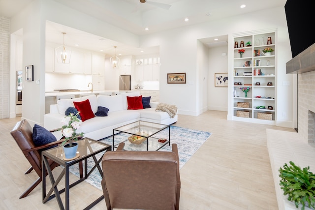 living room featuring light wood-type flooring, a brick fireplace, baseboards, and recessed lighting