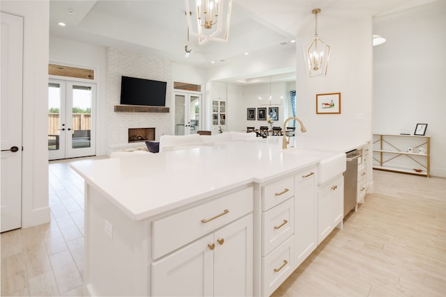 kitchen featuring french doors, a fireplace, light wood finished floors, open floor plan, and a sink