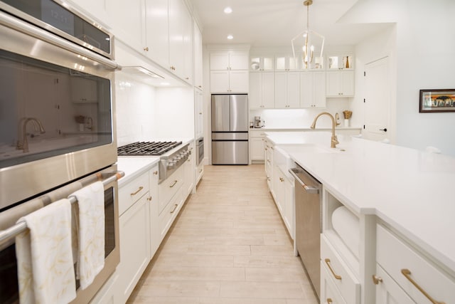 kitchen featuring recessed lighting, stainless steel appliances, a sink, white cabinetry, and light countertops