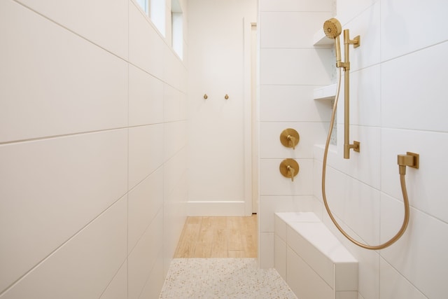 full bathroom with tiled shower and tile walls