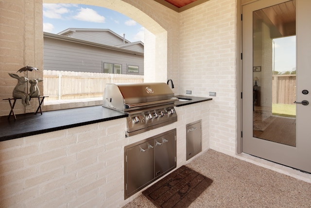 view of patio featuring a grill, fence, and exterior kitchen