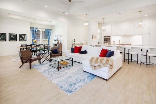 living area featuring light wood-style flooring, baseboards, and a notable chandelier