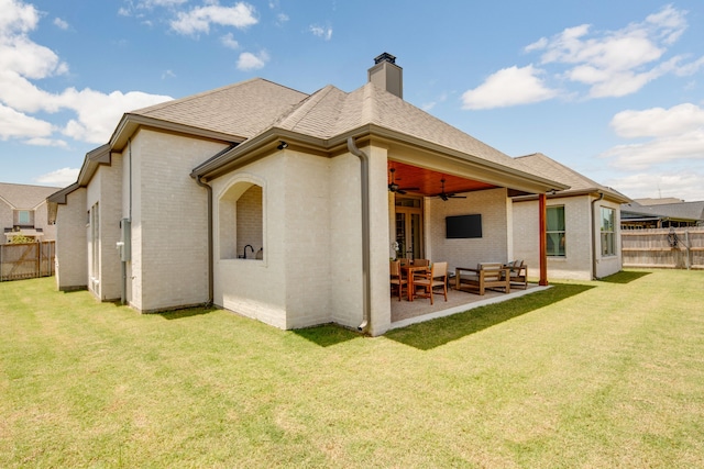 rear view of property featuring ceiling fan, a yard, brick siding, and fence