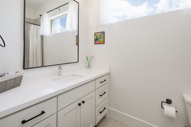 full bath with baseboards, vanity, and toilet