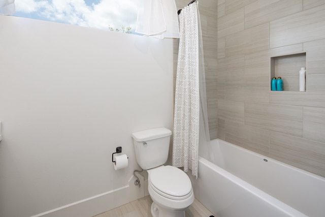 bathroom featuring toilet, baseboards, and shower / tub combo with curtain