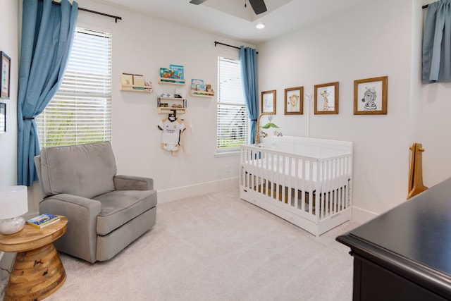 carpeted bedroom with a nursery area, recessed lighting, a ceiling fan, and baseboards