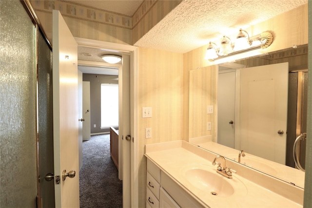 bathroom featuring wallpapered walls, a shower with door, a textured ceiling, and vanity