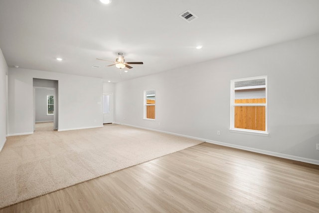 spare room with light wood-type flooring, baseboards, visible vents, and a ceiling fan