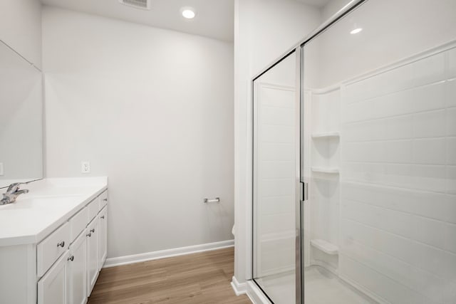 full bath featuring a stall shower, visible vents, baseboards, wood finished floors, and vanity