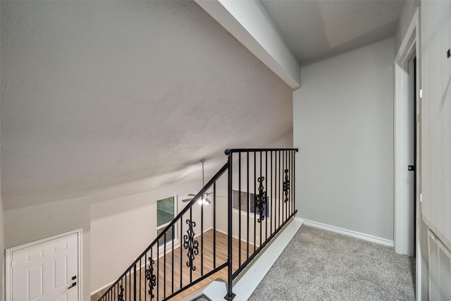 hall with carpet floors, baseboards, and an upstairs landing