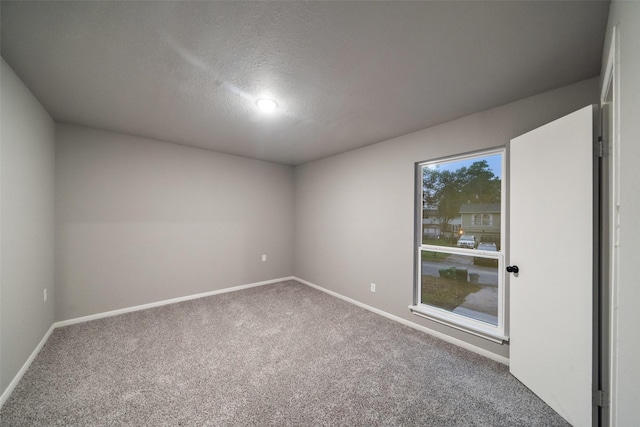 spare room featuring carpet floors, a textured ceiling, and baseboards