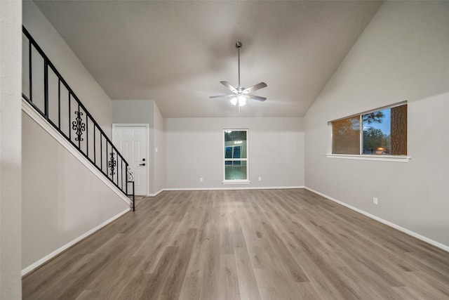 unfurnished living room with stairway, wood finished floors, a ceiling fan, and baseboards