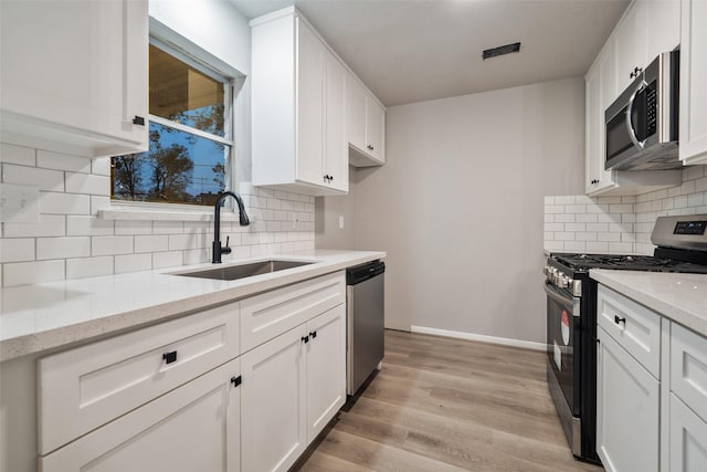 kitchen with stainless steel appliances, white cabinetry, and a sink