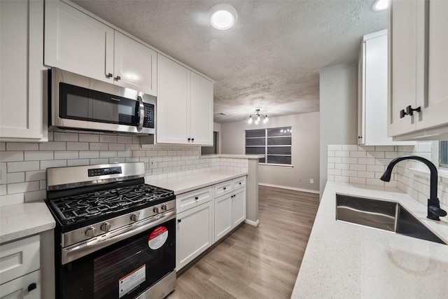 kitchen featuring light wood-type flooring, white cabinetry, appliances with stainless steel finishes, and a sink