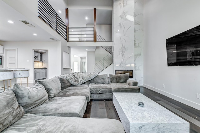 living room featuring stairs, visible vents, dark wood finished floors, and a premium fireplace