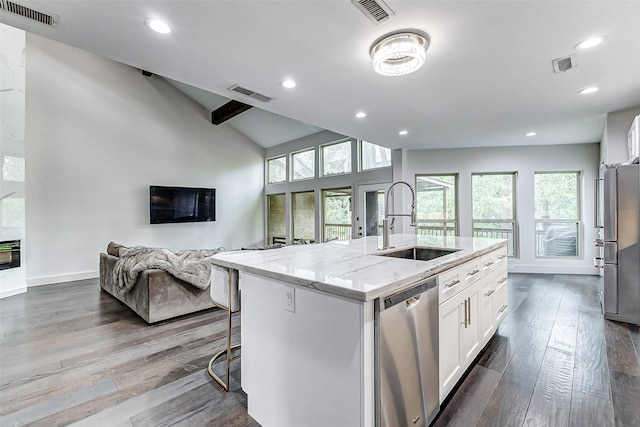 kitchen featuring stainless steel appliances, light stone counters, a sink, and visible vents