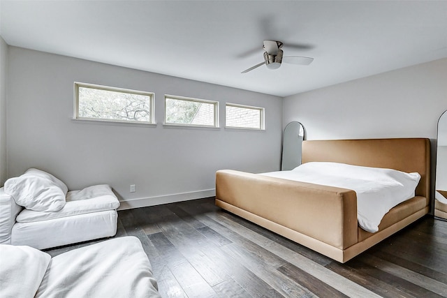 bedroom featuring a ceiling fan, multiple windows, baseboards, and dark wood-type flooring