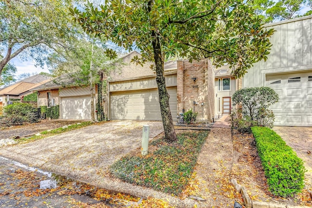 multi unit property featuring a garage, driveway, and brick siding