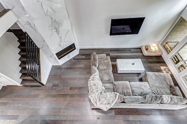 living room featuring stairs, a fireplace, wood finished floors, and baseboards