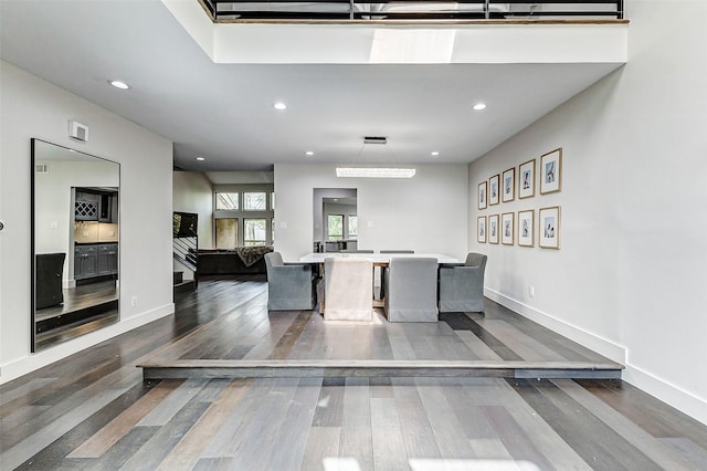 kitchen featuring baseboards, a kitchen island, wood finished floors, light countertops, and recessed lighting