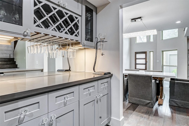 kitchen featuring dark countertops, glass insert cabinets, light wood-type flooring, and white cabinetry