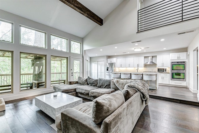 living area featuring dark wood-type flooring, plenty of natural light, and beam ceiling