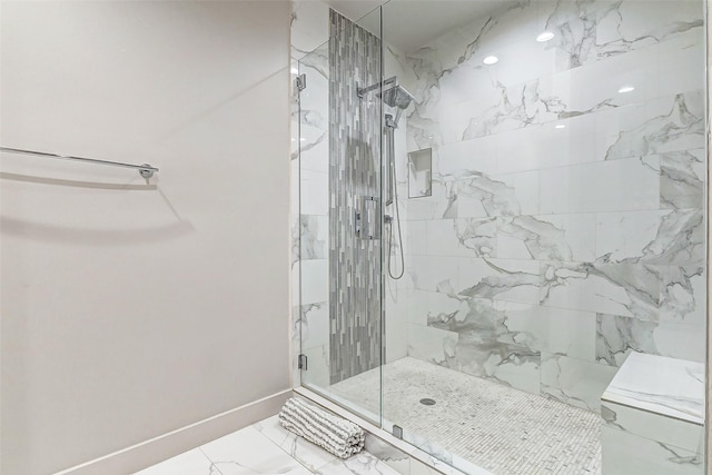 bathroom featuring marble finish floor, tiled shower, and baseboards