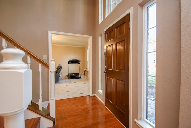 foyer entrance featuring wood finished floors, stairs, and ornamental molding