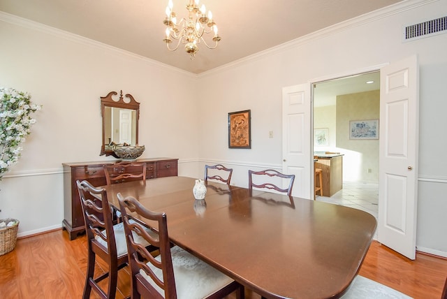 dining room featuring ornamental molding, a notable chandelier, visible vents, and light wood-type flooring